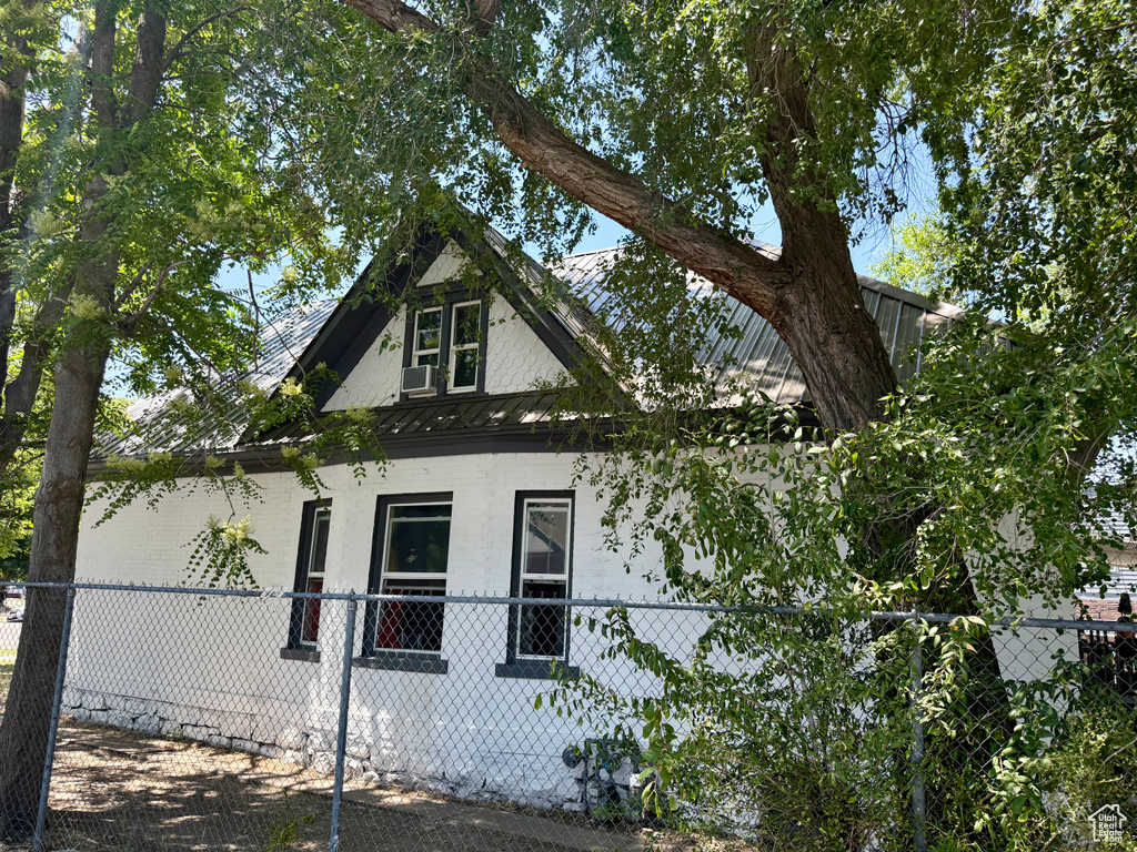 View of side of property featuring a fenced front yard, a standing seam roof, and a metal roof