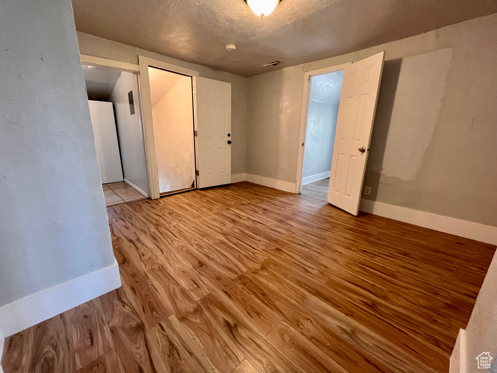 Unfurnished room featuring wood finished floors, a textured ceiling, and a smoke detector
