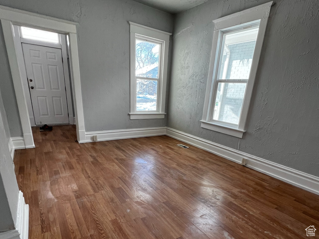 Unfurnished living room with wood finished floors and a textured wall