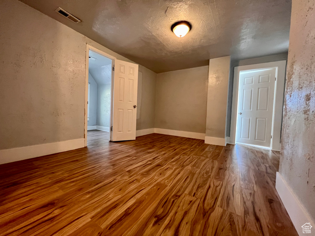 Empty room featuring wood finished floors and a textured ceiling