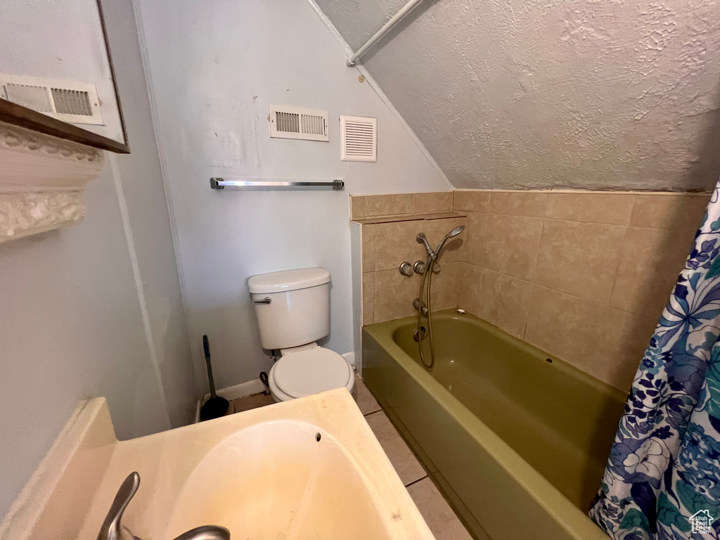 Bathroom with a textured ceiling, a garden tub, lofted ceiling, and tile patterned flooring