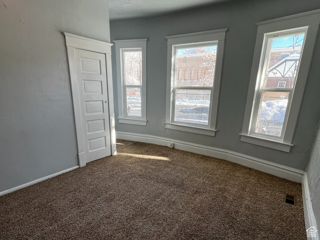 Spare room featuring plenty of natural light, carpet, and a textured ceiling