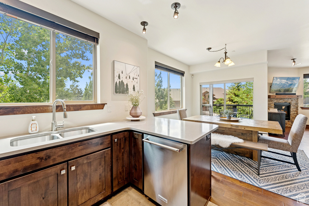 Kitchen with dishwasher, light countertops, dark brown cabinets, a glass covered fireplace, and open floor plan