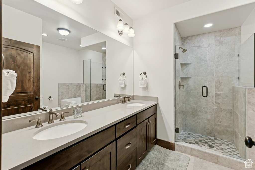 Full bathroom featuring double vanity, a shower stall, a tub, and tile patterned flooring
