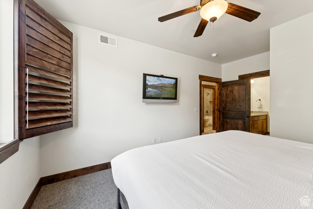 Carpeted bedroom with ensuite bath and a ceiling fan
