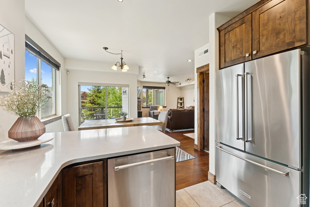 Kitchen featuring appliances with stainless steel finishes, a chandelier, light countertops, open floor plan, and a peninsula