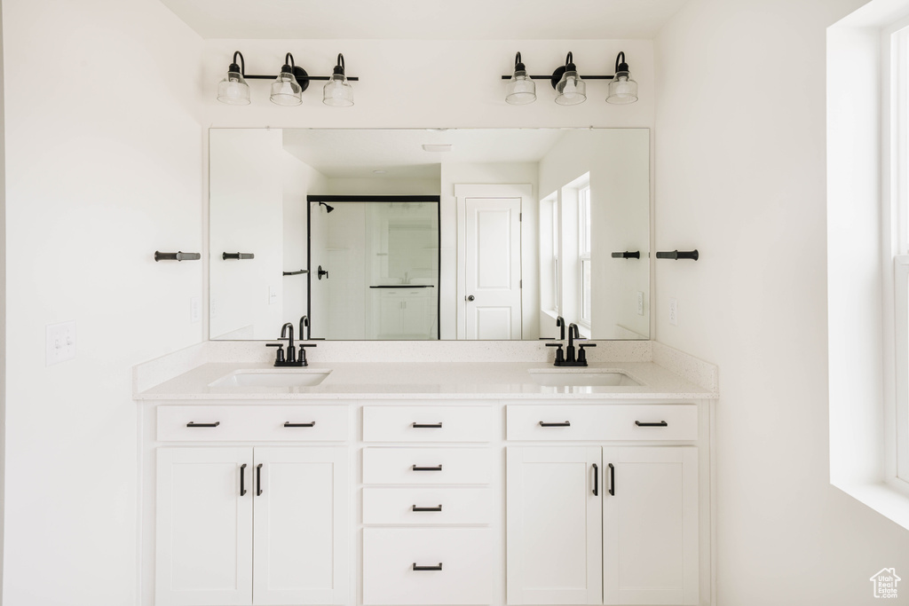 Bathroom featuring a stall shower and double vanity
