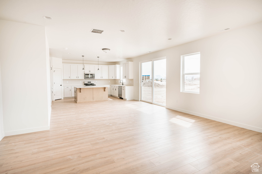 Unfurnished living room featuring baseboards and light wood-type flooring