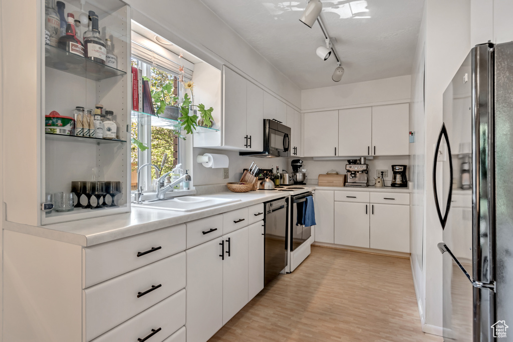 Kitchen featuring freestanding refrigerator, white electric range, black microwave, white cabinets, and dishwasher