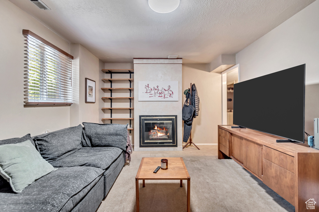 Living area featuring light carpet, a fireplace, and a textured ceiling