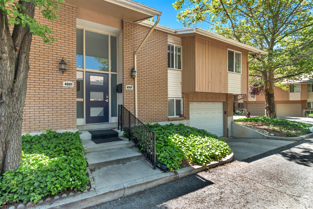 Entrance to property with an attached garage, brick siding, and concrete driveway