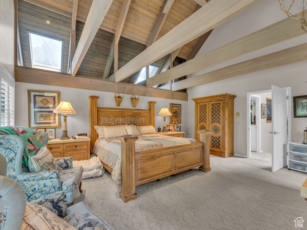 Bedroom with a skylight, a wood ceiling with exposed beams, carpet, multiple windows, and high vaulted ceiling