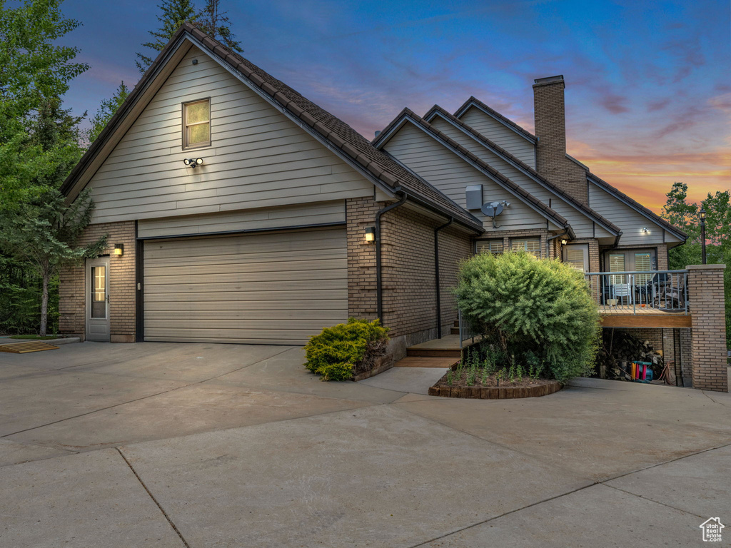 View of front of house with a chimney, a garage, brick siding, and concrete driveway