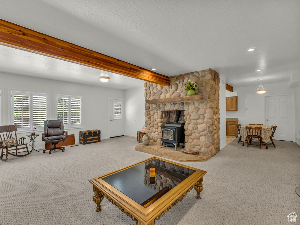 Living area with carpet floors, a wood stove, beam ceiling, recessed lighting, and a textured ceiling
