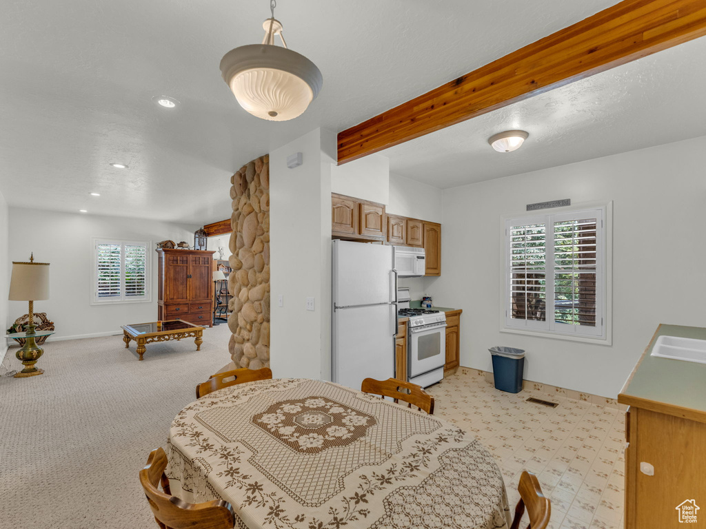 Dining space featuring healthy amount of natural light, beamed ceiling, light carpet, and recessed lighting