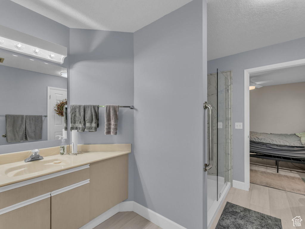 Bathroom with vanity, a shower stall, connected bathroom, and wood finished floors