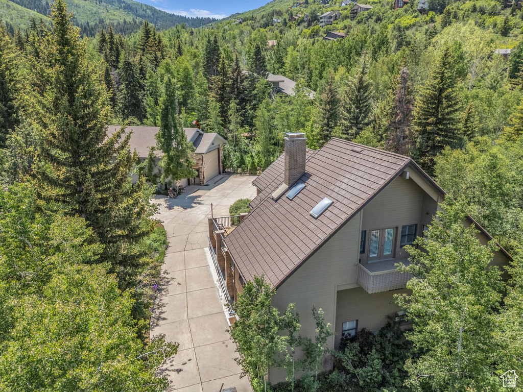 Aerial view of property and surrounding area with a heavily wooded area and a mountainous background