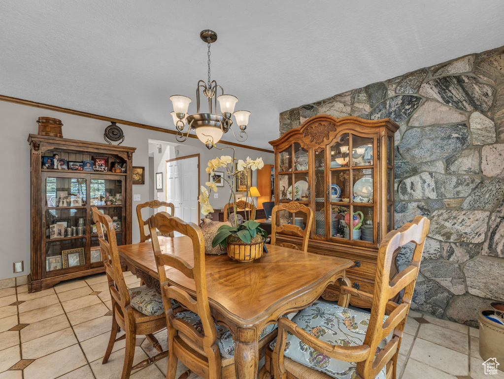 Dining space featuring a chandelier, light tile patterned floors, and crown molding