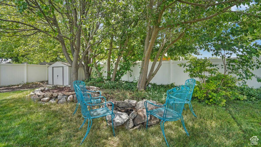 Fenced backyard featuring an outdoor fire pit and a storage unit