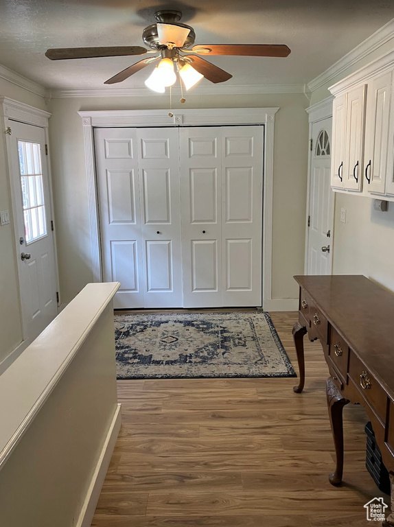 Entrance foyer with ornamental molding, ceiling fan, and wood finished floors