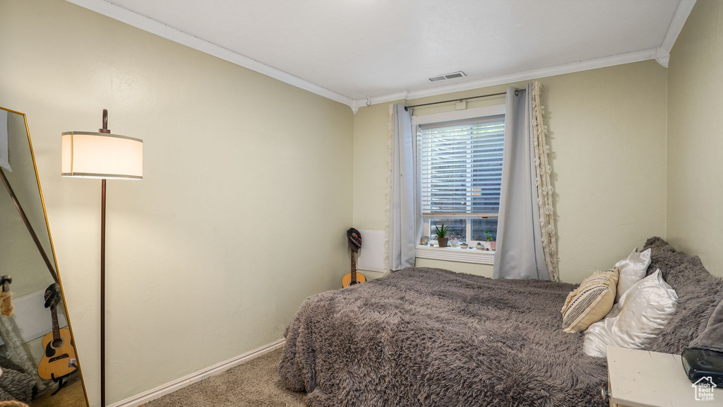 Carpeted bedroom featuring crown molding and baseboards