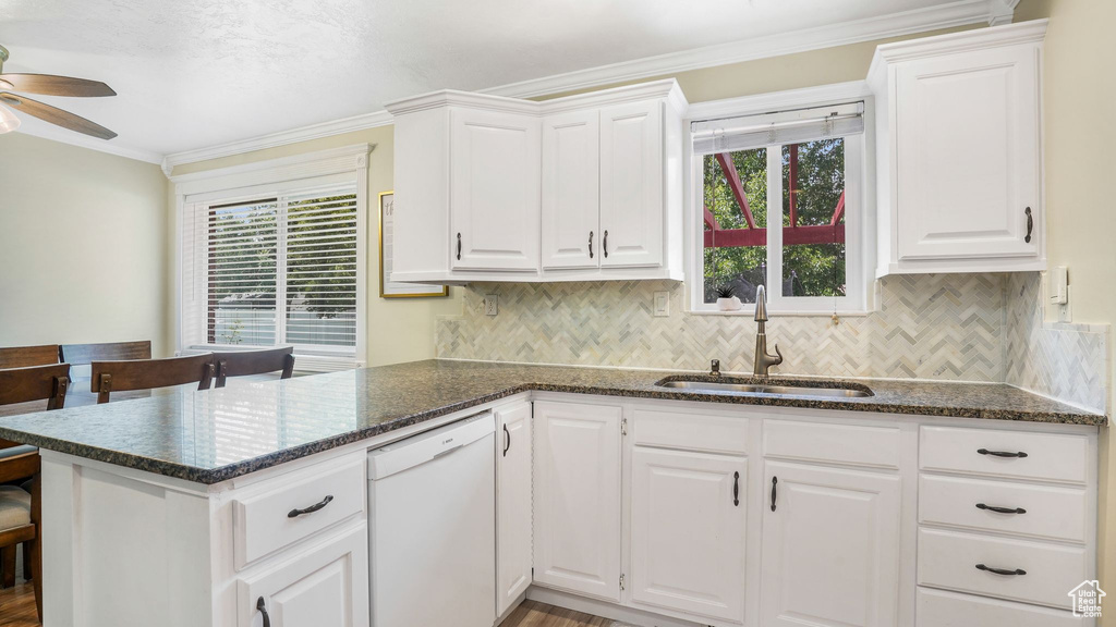 Kitchen featuring dishwasher, a ceiling fan, white cabinetry, a peninsula, and tasteful backsplash