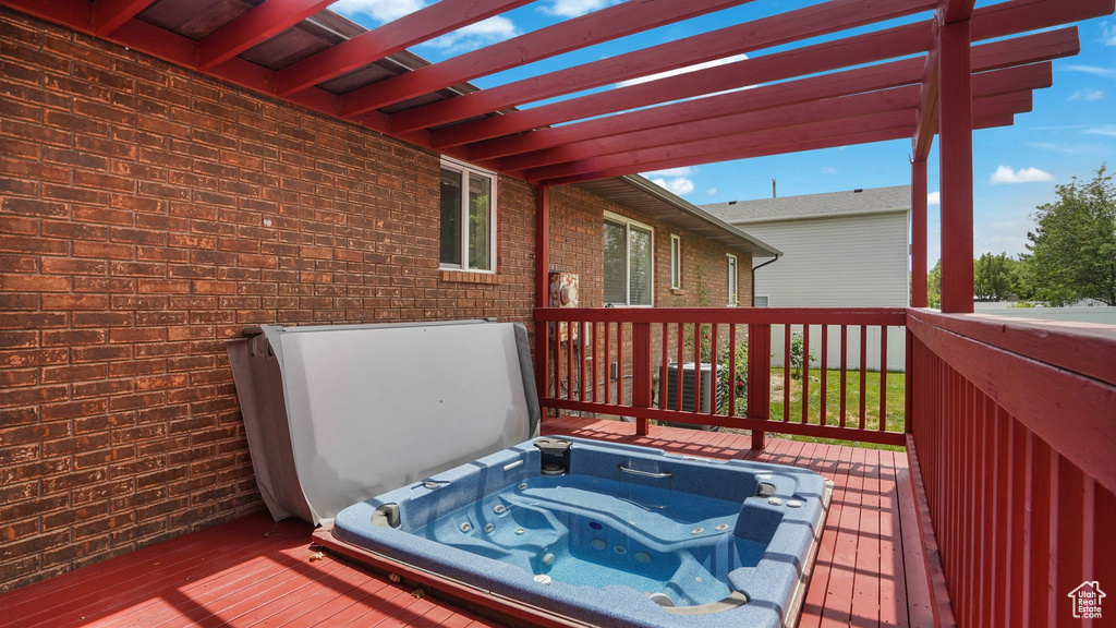 Deck featuring a covered hot tub and a pergola
