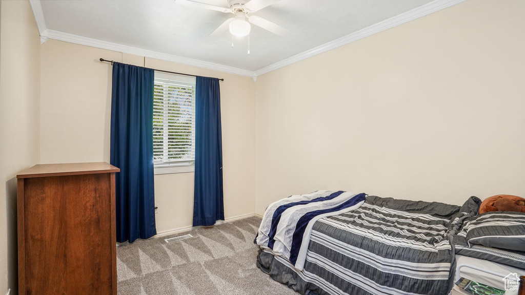 Bedroom with light colored carpet, crown molding, and ceiling fan