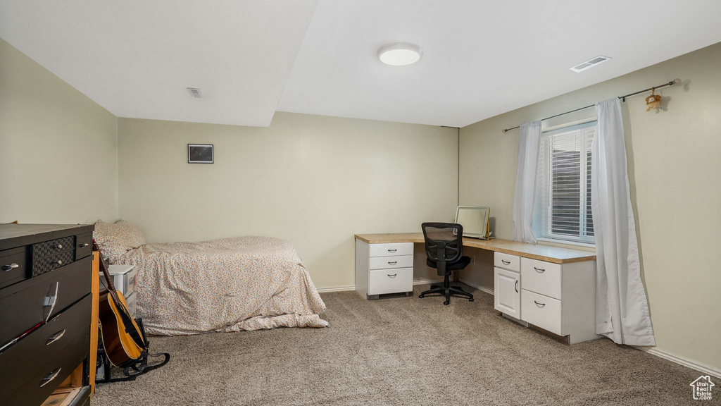 Bedroom featuring light carpet and an office area