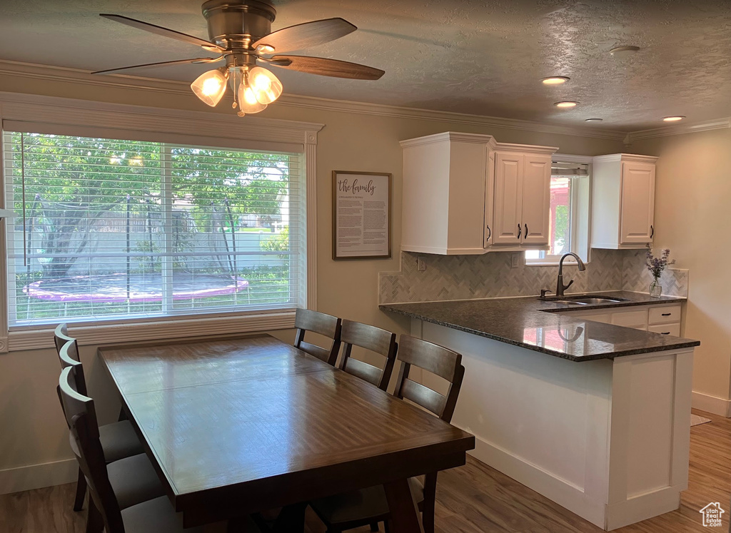 Dining space with crown molding, light wood-style floors, ceiling fan, and a textured ceiling