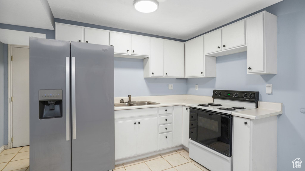 Kitchen with stainless steel fridge with ice dispenser, electric range, light tile patterned floors, and white cabinetry