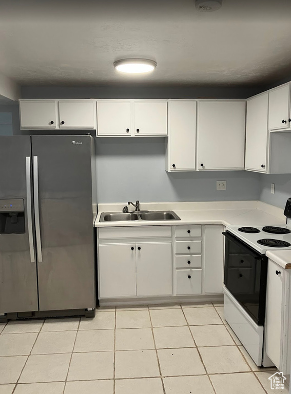 Kitchen featuring stainless steel refrigerator with ice dispenser, electric range, white cabinets, and light countertops