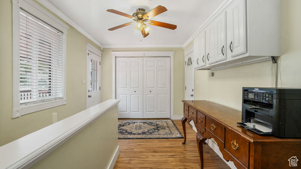 Home office with a ceiling fan, light wood-style floors, and crown molding