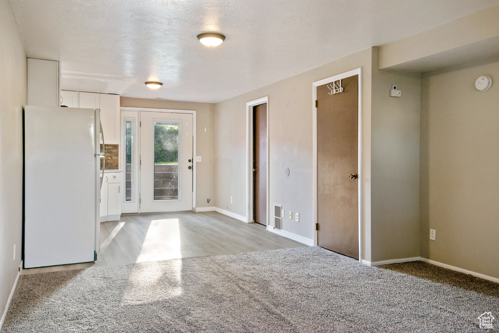 Foyer entrance featuring baseboards and light carpet