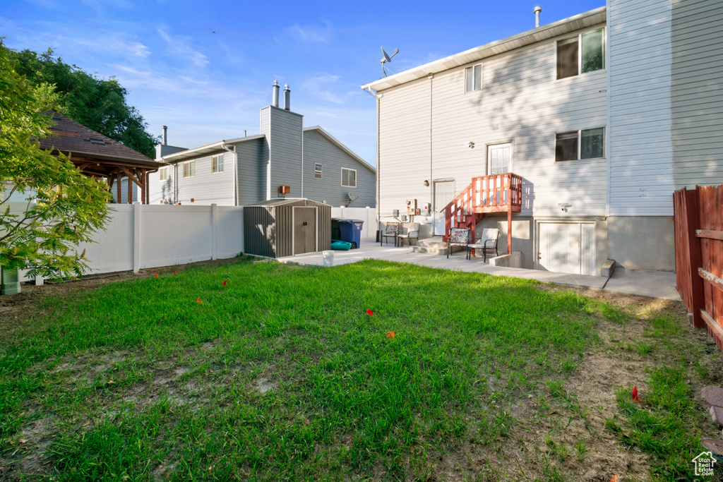 Rear view of house featuring a shed, a fenced backyard, and a patio area