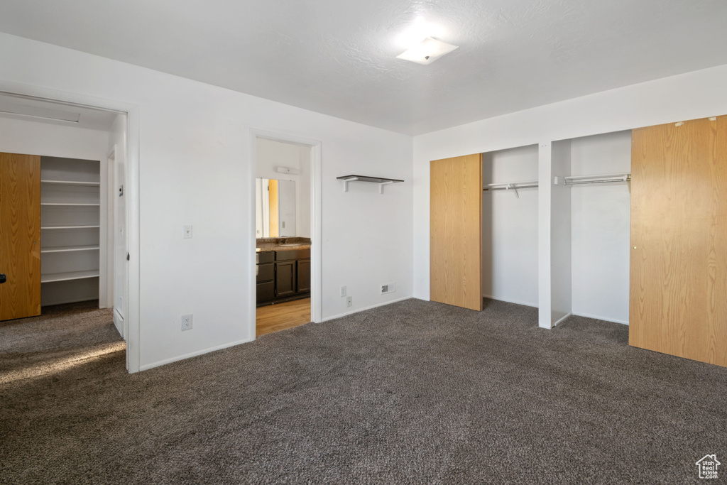 Unfurnished bedroom with carpet, two closets, and ensuite bathroom