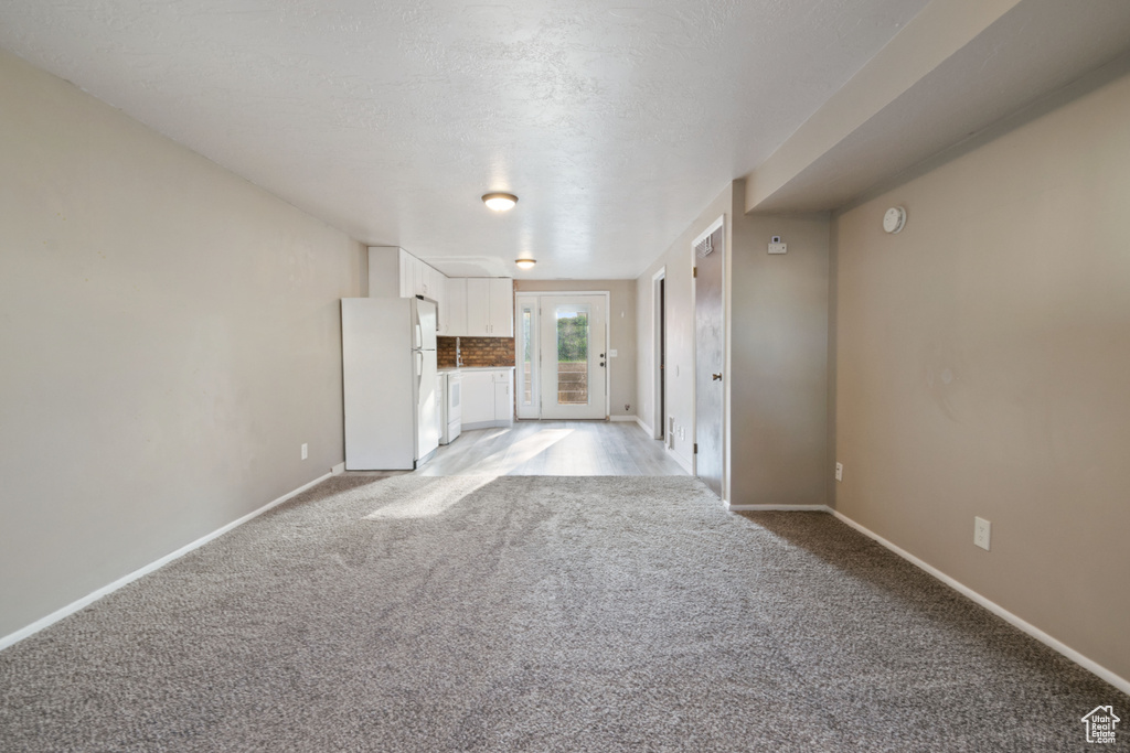 Unfurnished living room with light carpet and baseboards