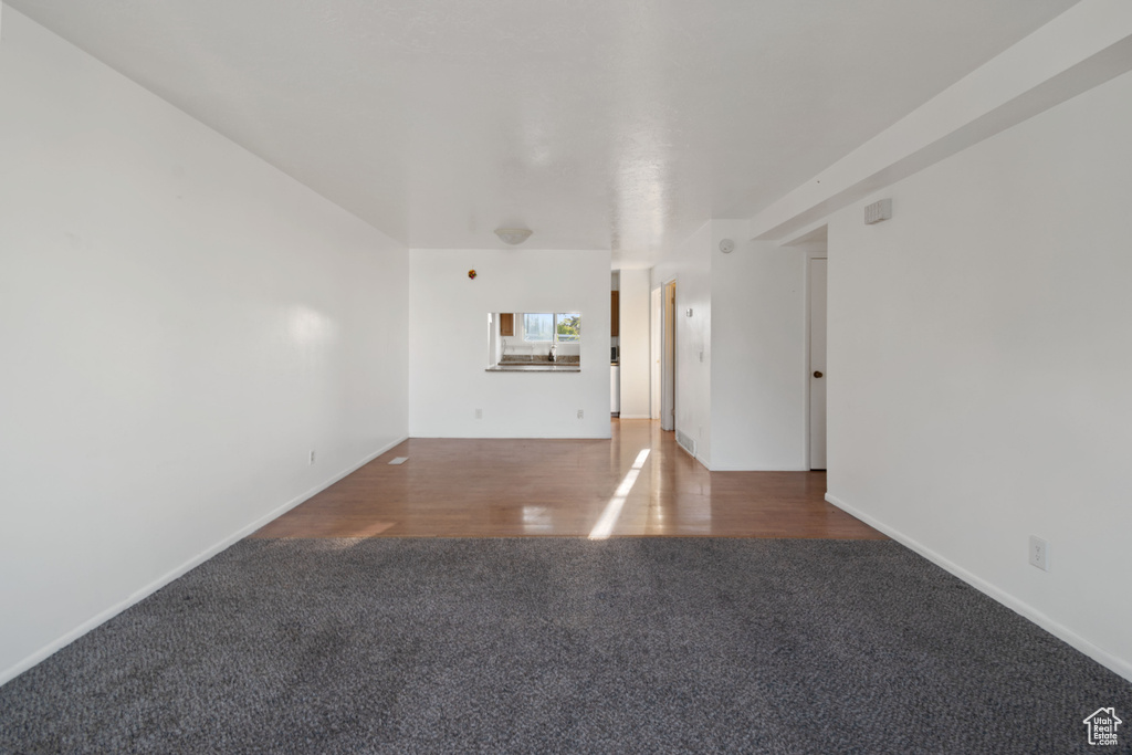 Unfurnished living room featuring carpet floors and baseboards