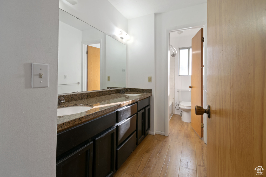 Full bath with double vanity, hardwood / wood-style floors, and shower / tub combination