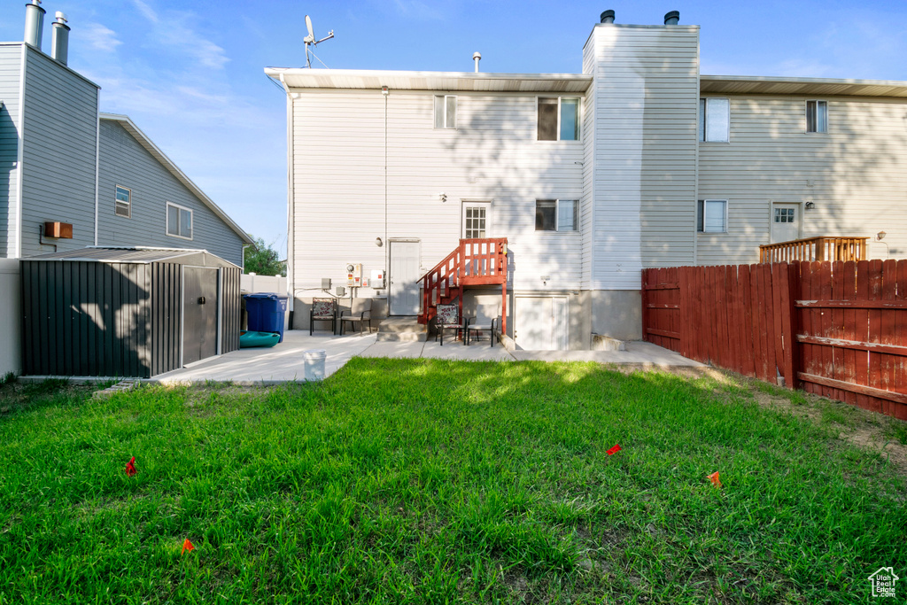 Back of house with a patio area, a storage unit, a fenced backyard, and a chimney