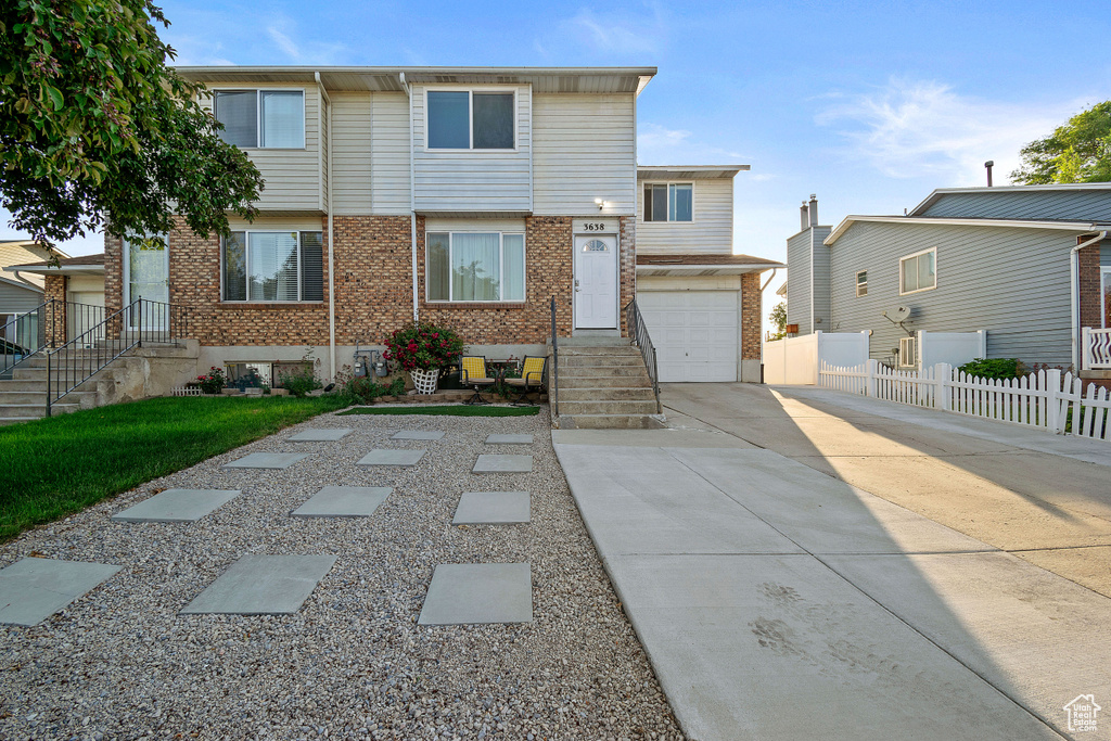 View of property with brick siding, concrete driveway, and an attached garage