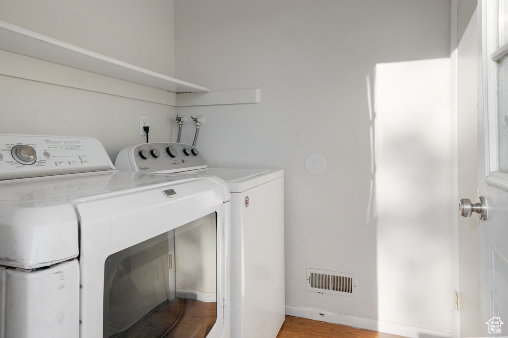 Washroom with washer and clothes dryer and light wood-style floors