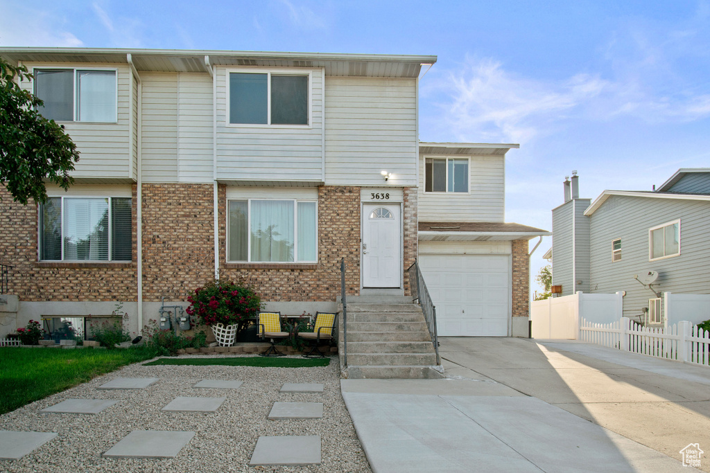Townhome / multi-family property with brick siding, driveway, and an attached garage