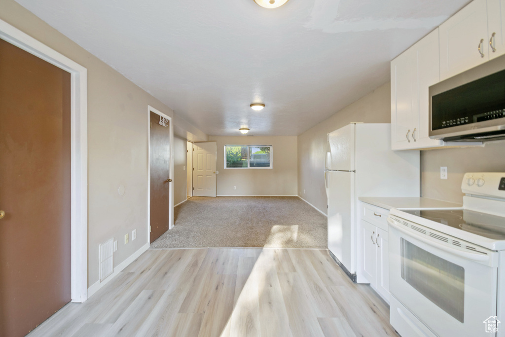Kitchen with white appliances, white cabinetry, light wood finished floors, light countertops, and open floor plan