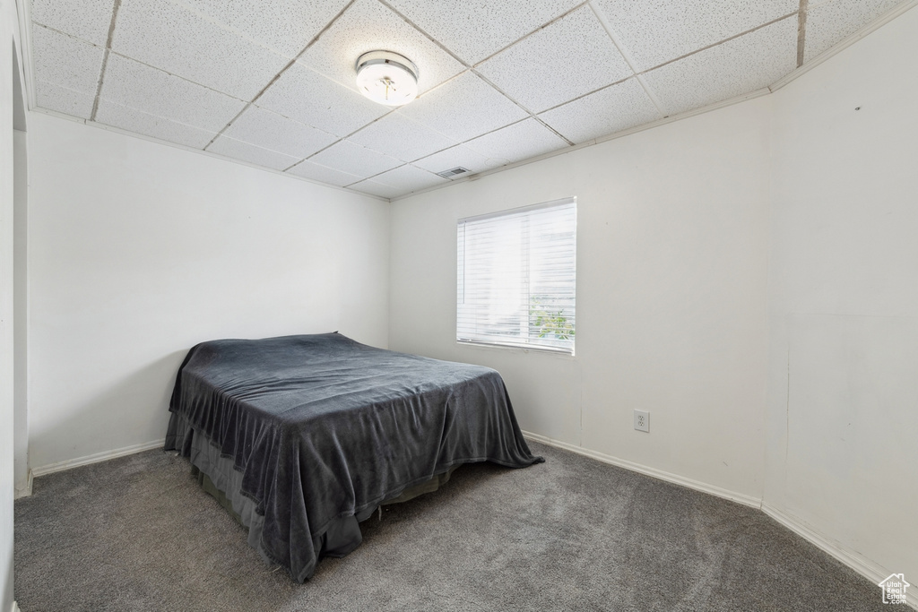 Carpeted bedroom featuring a drop ceiling and baseboards