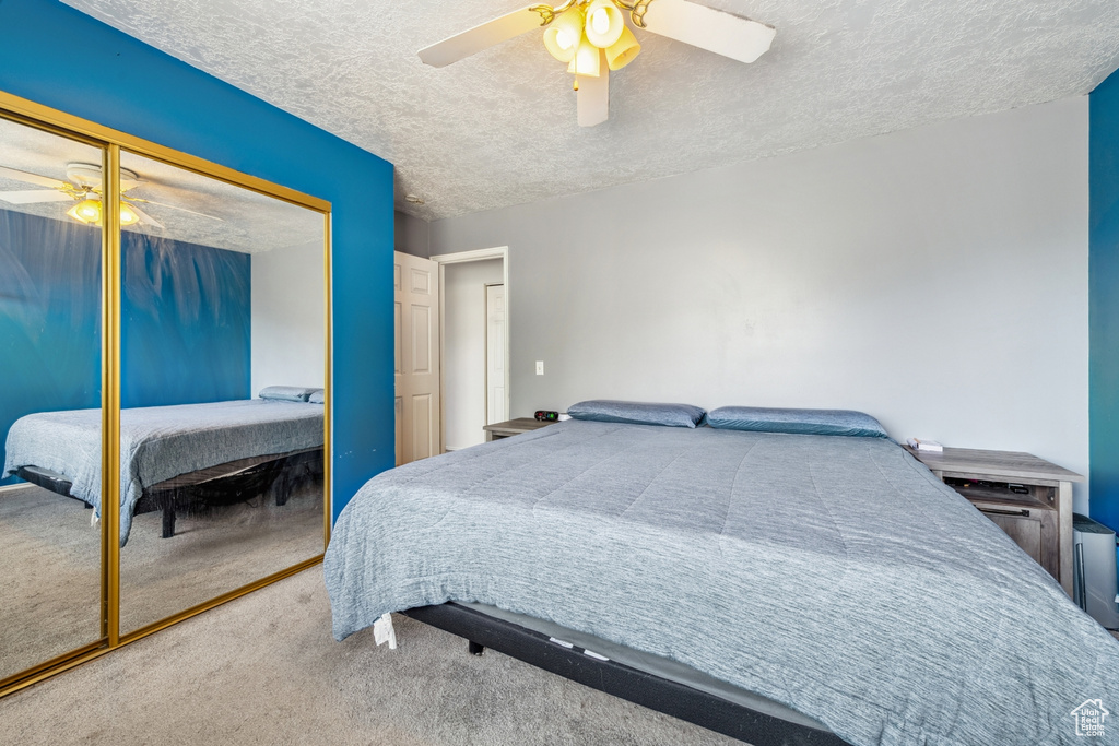 Bedroom featuring carpet floors, a textured ceiling, a closet, and a ceiling fan