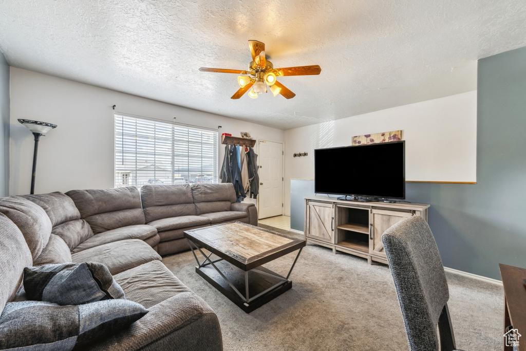 Living area with ceiling fan, light carpet, and a textured ceiling