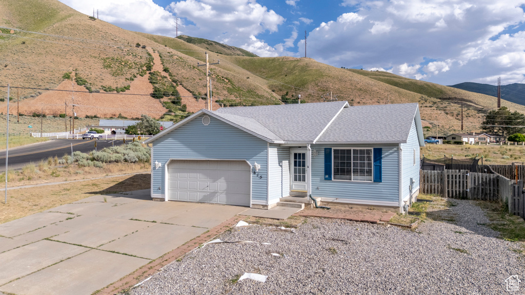 Ranch-style house with driveway, a garage, a mountain view, and a shingled roof