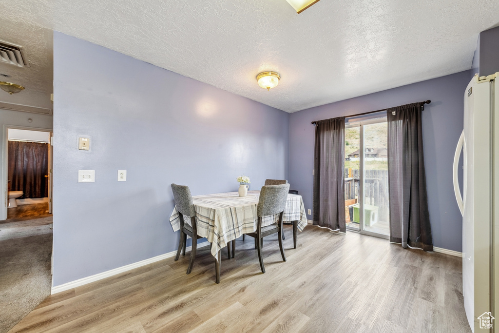 Dining space featuring a textured ceiling and light wood finished floors