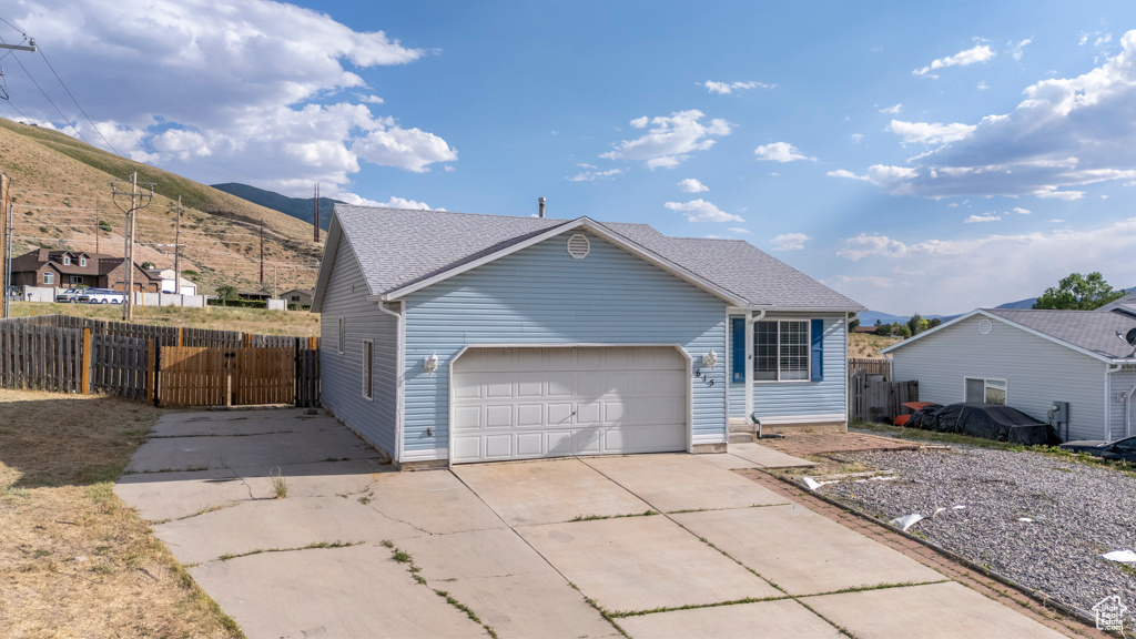 View of front of house featuring driveway, a gate, a garage, and a mountain view